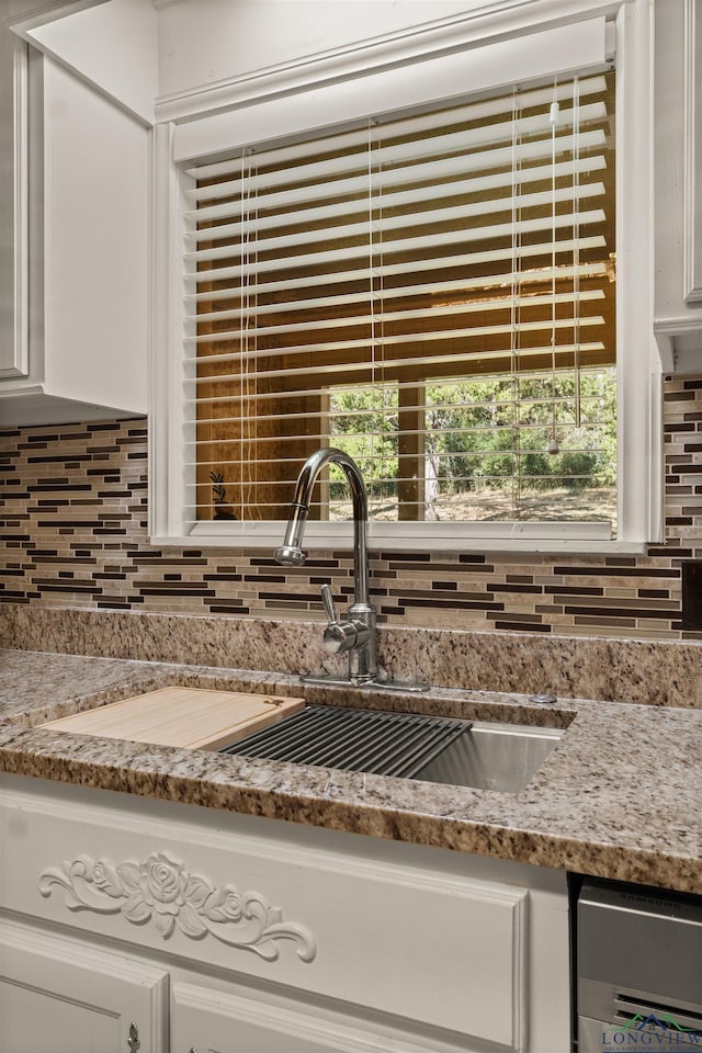 details with backsplash, white cabinets, and sink