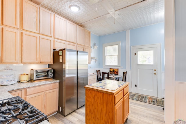 kitchen featuring stainless steel fridge, a kitchen island, light hardwood / wood-style flooring, and light brown cabinetry