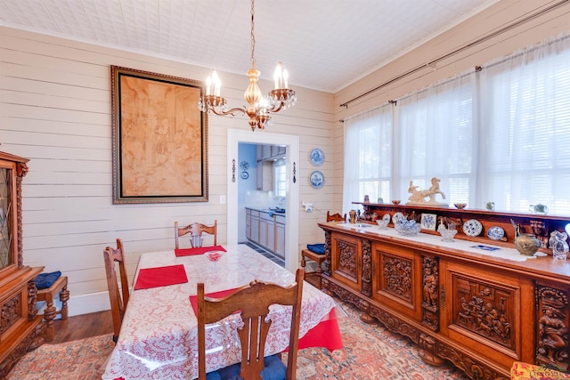 dining space featuring wood walls, a chandelier, and dark hardwood / wood-style floors