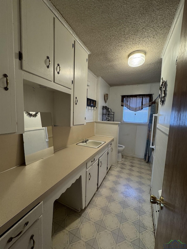 kitchen featuring white cabinets, a textured ceiling, and sink