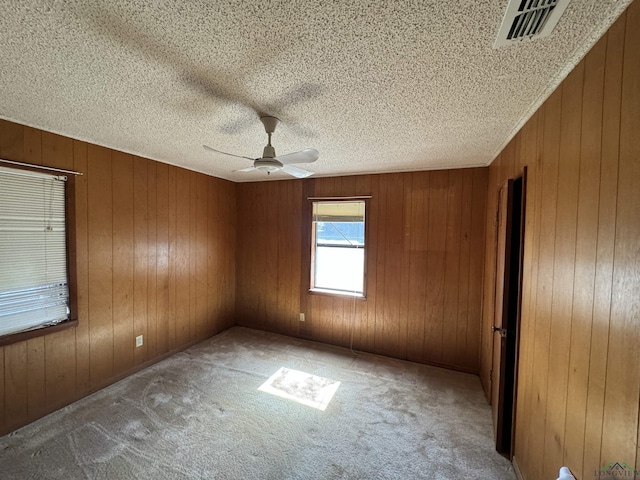 carpeted empty room featuring ceiling fan and wooden walls