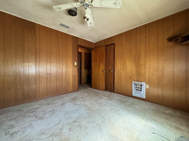 unfurnished bedroom with heating unit, wood walls, and ceiling fan