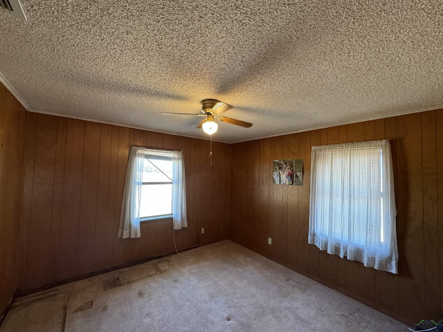 unfurnished room with carpet, ceiling fan, a textured ceiling, and wooden walls