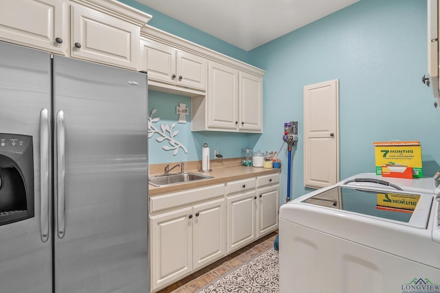 kitchen featuring independent washer and dryer, light countertops, white cabinetry, stainless steel refrigerator with ice dispenser, and a sink