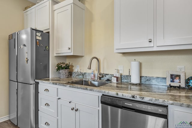 kitchen featuring appliances with stainless steel finishes, white cabinets, a sink, and light stone countertops