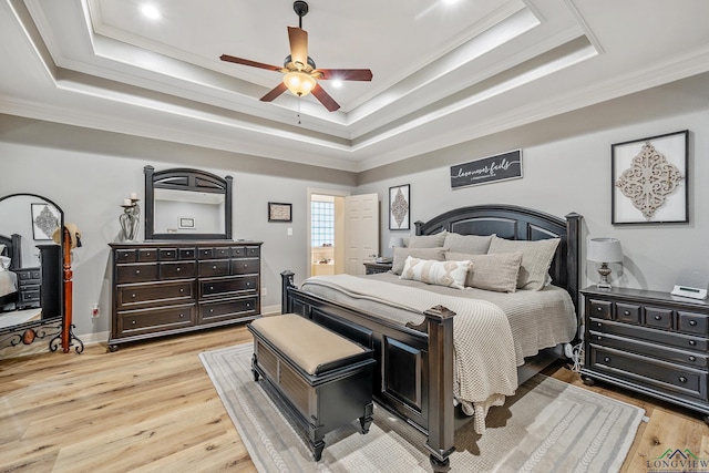 bedroom with light wood-style floors, ornamental molding, and a raised ceiling