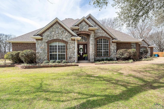 french country home with a shingled roof, brick siding, and a front lawn