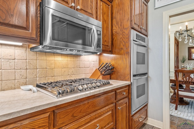 kitchen featuring appliances with stainless steel finishes, light countertops, brown cabinets, and decorative backsplash