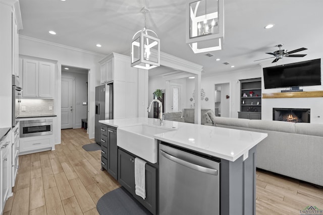 kitchen with crown molding, stainless steel appliances, a sink, and open floor plan