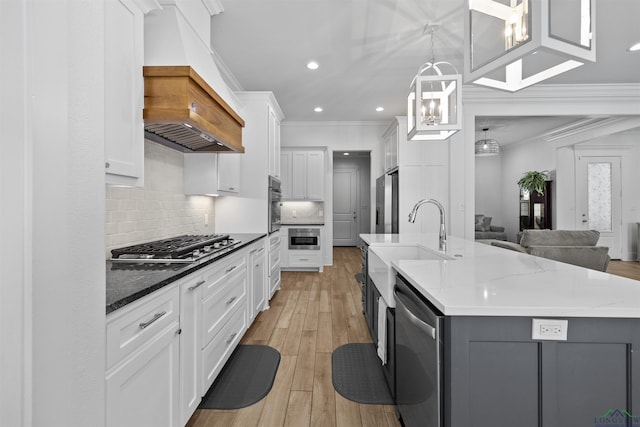 kitchen with stainless steel appliances, premium range hood, a sink, open floor plan, and crown molding