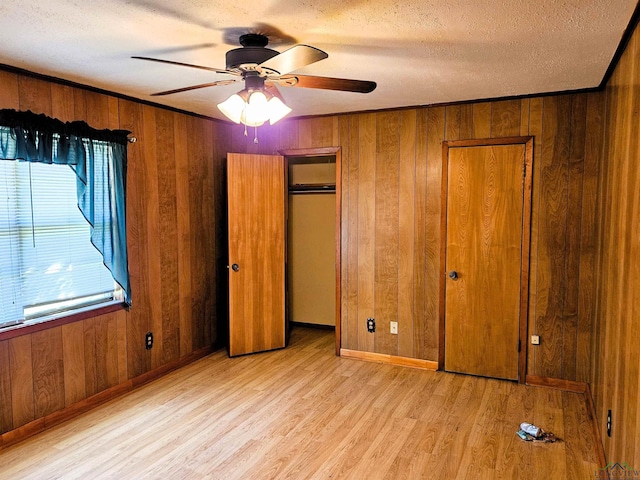 unfurnished bedroom featuring a textured ceiling, ceiling fan, and wood walls