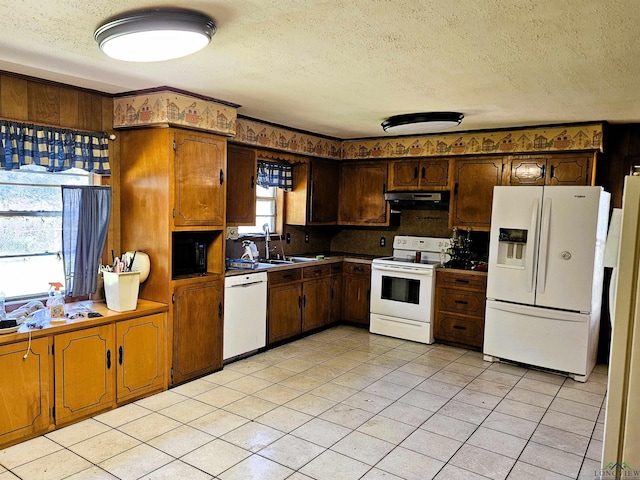 kitchen featuring a textured ceiling, sink, light tile patterned flooring, and white appliances