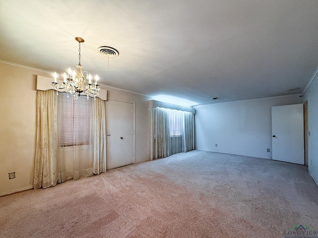 spare room featuring carpet flooring, ornamental molding, and a notable chandelier