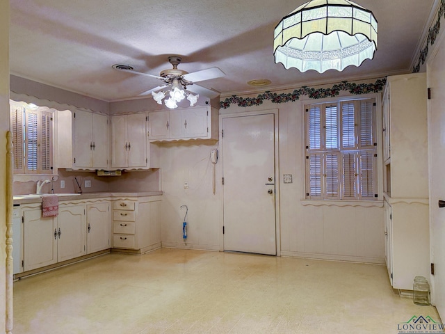 kitchen featuring white cabinetry, sink, ceiling fan, crown molding, and a textured ceiling