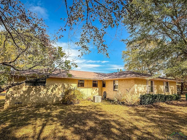 rear view of house featuring a lawn and central AC