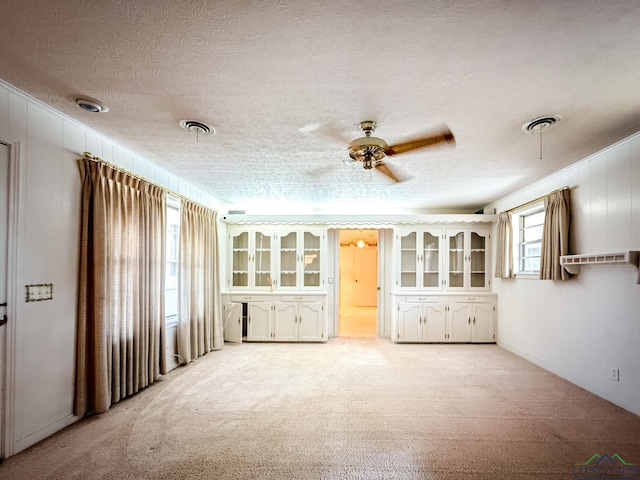 carpeted empty room featuring a wealth of natural light, ceiling fan, and a textured ceiling