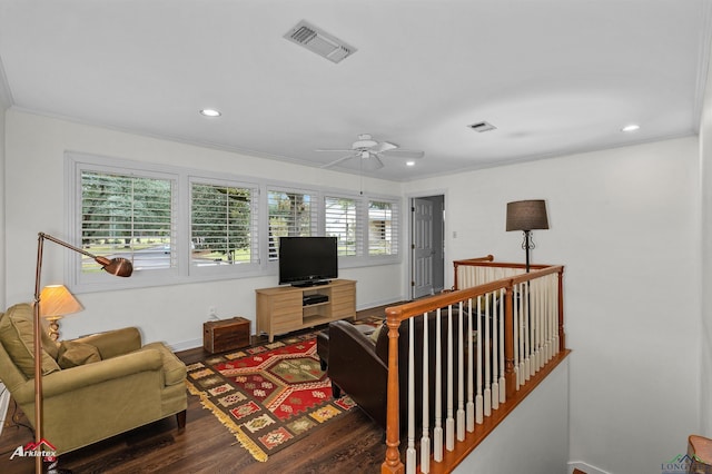 living room with ceiling fan, plenty of natural light, dark wood-type flooring, and ornamental molding