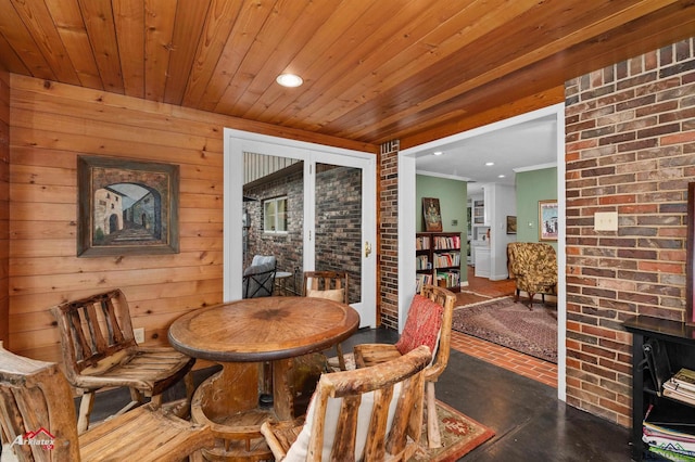 dining room with wood walls, wood ceiling, ornamental molding, and brick wall