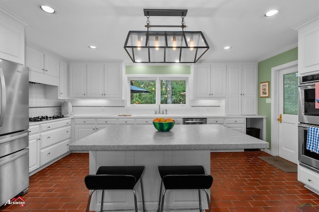 kitchen featuring hanging light fixtures, appliances with stainless steel finishes, tasteful backsplash, a kitchen island, and white cabinetry