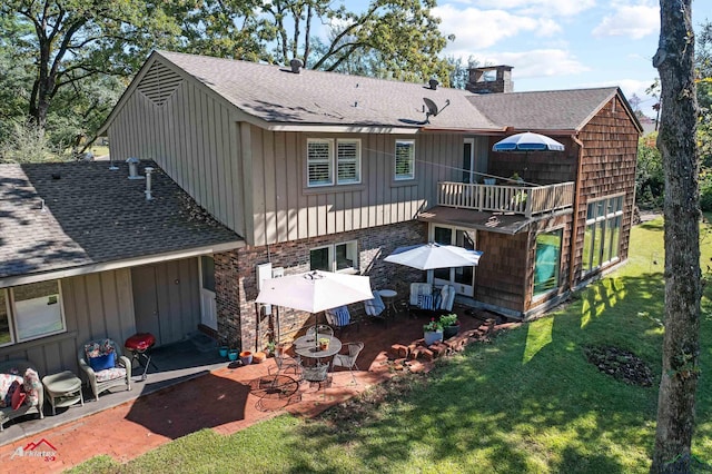 rear view of property with a balcony, a patio area, and a lawn