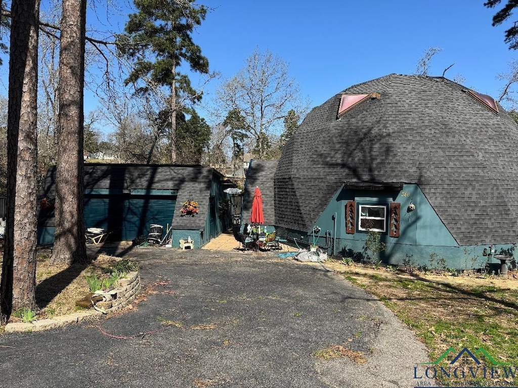 view of home's exterior featuring driveway and a shingled roof