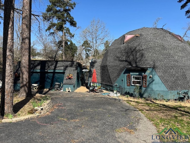 view of home's exterior featuring driveway and a shingled roof