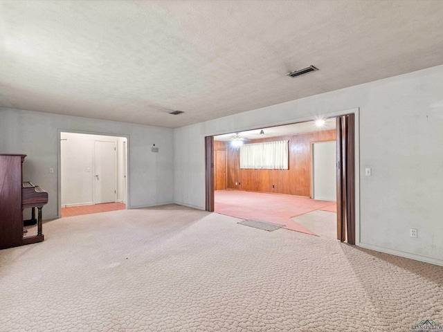 spare room with a textured ceiling, visible vents, and light colored carpet