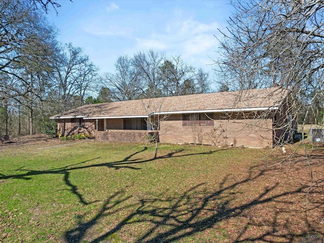 back of property with brick siding and a yard