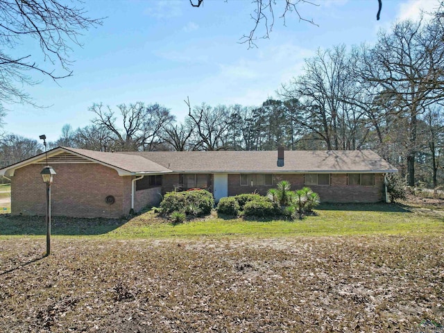 single story home with a chimney, a front lawn, and brick siding