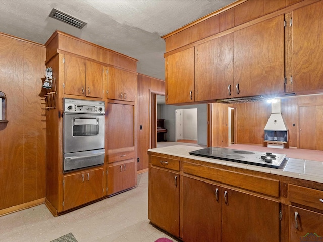 kitchen with black electric cooktop, visible vents, stainless steel oven, a warming drawer, and light floors