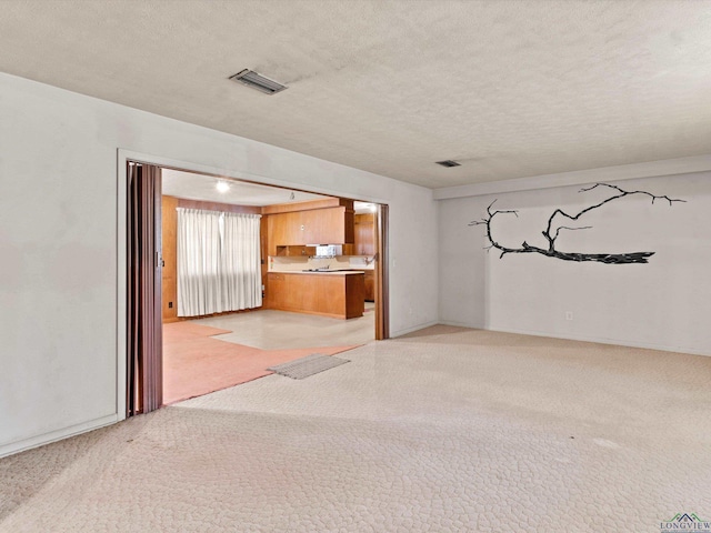 unfurnished living room featuring light carpet, visible vents, and a textured ceiling