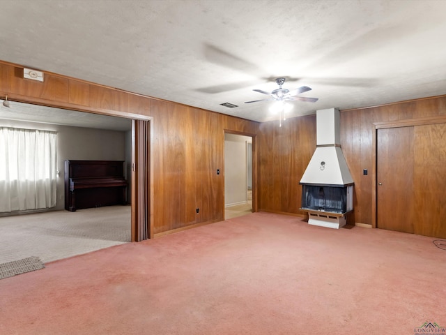 interior space featuring light carpet, wood walls, visible vents, and a ceiling fan