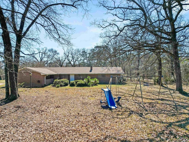 back of property featuring brick siding and a playground