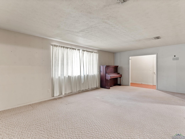 unfurnished room with baseboards, visible vents, a textured ceiling, and carpet flooring