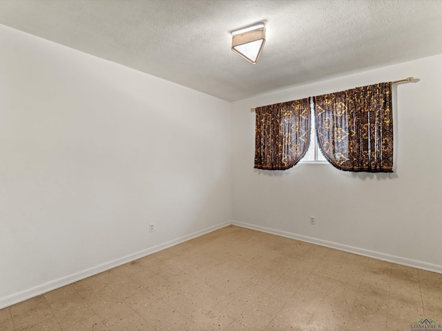 spare room with baseboards, a textured ceiling, and tile patterned floors