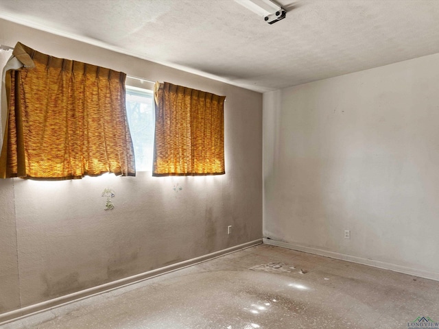 unfurnished room with a textured ceiling and baseboards