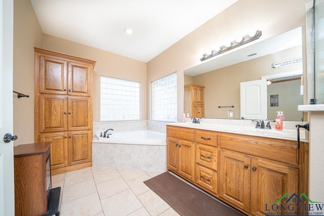 bathroom with tile patterned flooring, vanity, and tiled tub