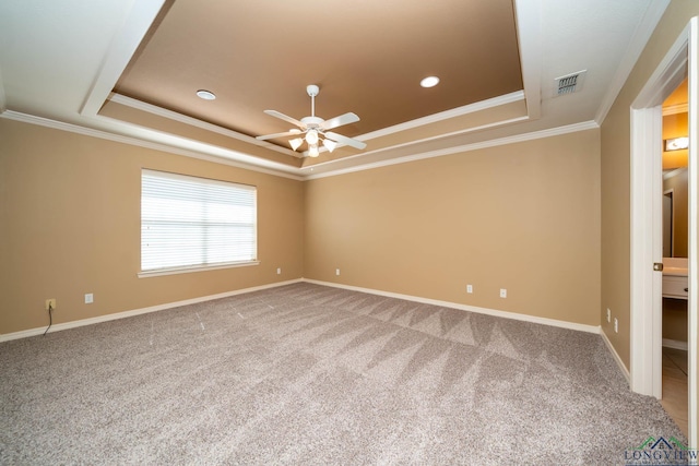 carpeted spare room with ornamental molding, a tray ceiling, visible vents, and baseboards