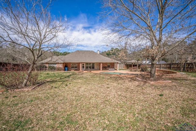 rear view of property with brick siding, fence, a patio, and a lawn