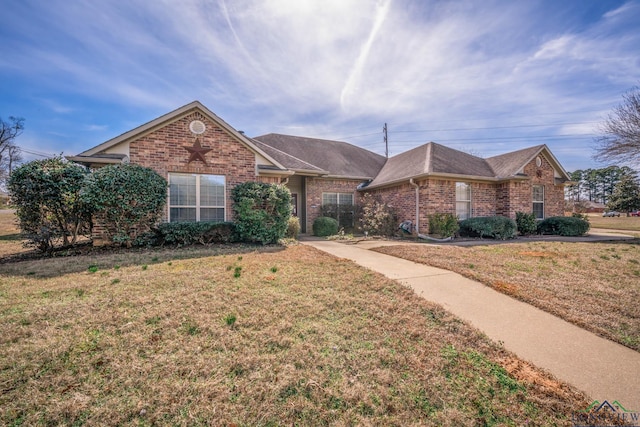 ranch-style home featuring brick siding, a front yard, and a shingled roof