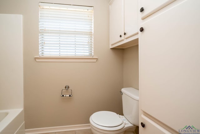 bathroom featuring a bathtub, toilet, and baseboards