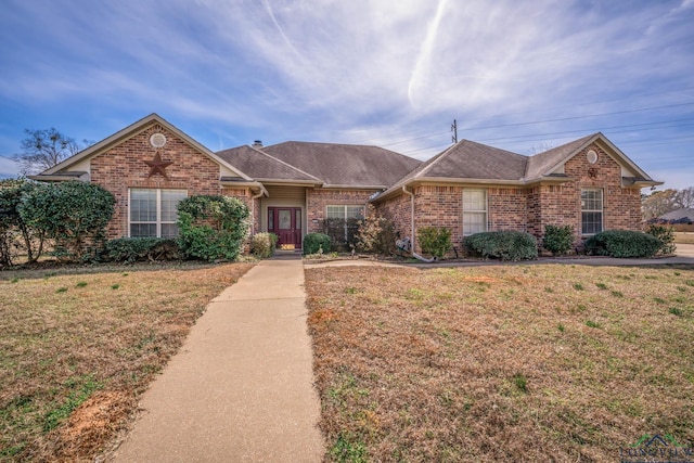 ranch-style house featuring a front yard, brick siding, and roof with shingles