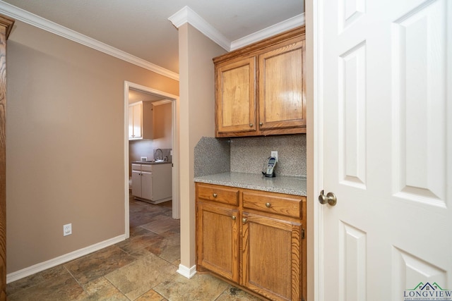 kitchen with baseboards, light countertops, ornamental molding, decorative backsplash, and stone finish flooring