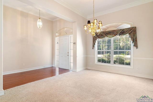 carpeted spare room with ornamental molding and an inviting chandelier