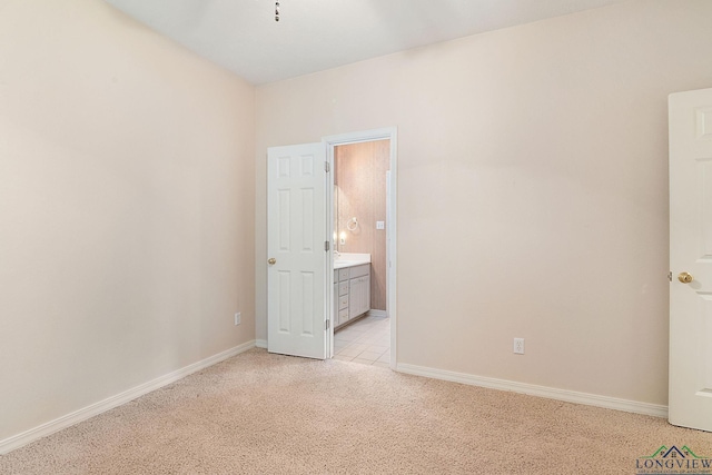 unfurnished bedroom featuring light carpet and ensuite bathroom