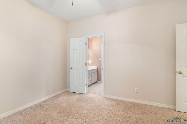 unfurnished bedroom featuring light carpet and ensuite bathroom