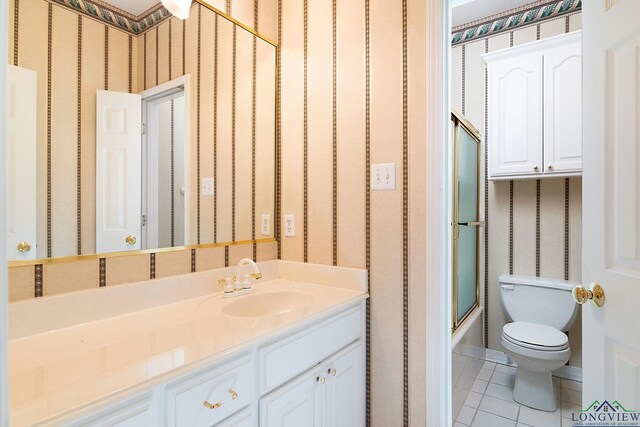 full bathroom featuring tile patterned floors, vanity, toilet, and bath / shower combo with glass door