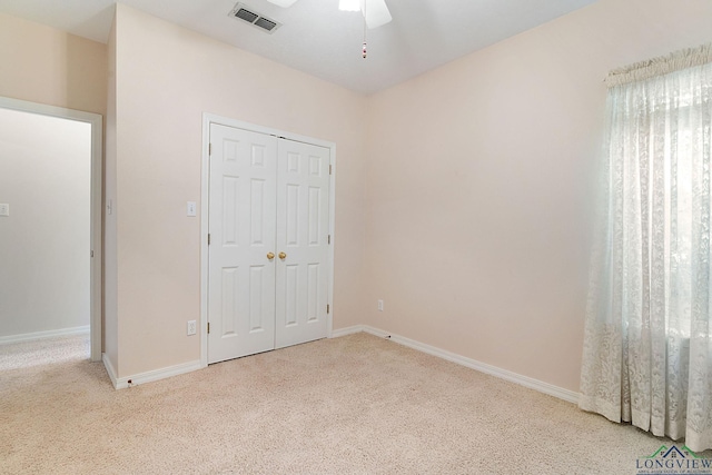 unfurnished bedroom featuring ceiling fan, light colored carpet, and a closet