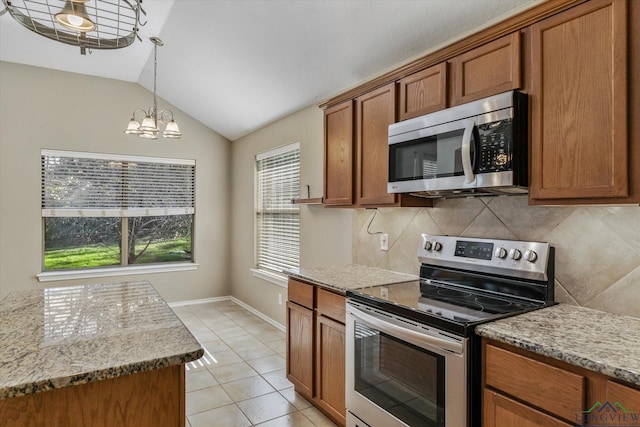 kitchen with stainless steel appliances, light stone counters, a notable chandelier, vaulted ceiling, and light tile patterned flooring