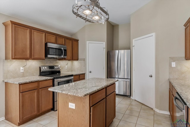 kitchen with decorative backsplash, light stone counters, stainless steel appliances, light tile patterned floors, and a center island